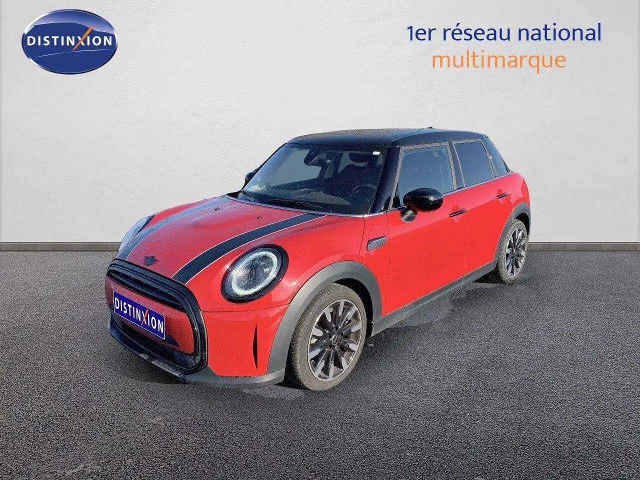 Vue 3/4 avant droite d'une MINI 1.5 136CH rouge chili avec toit noir et bandes noires sur le capot.