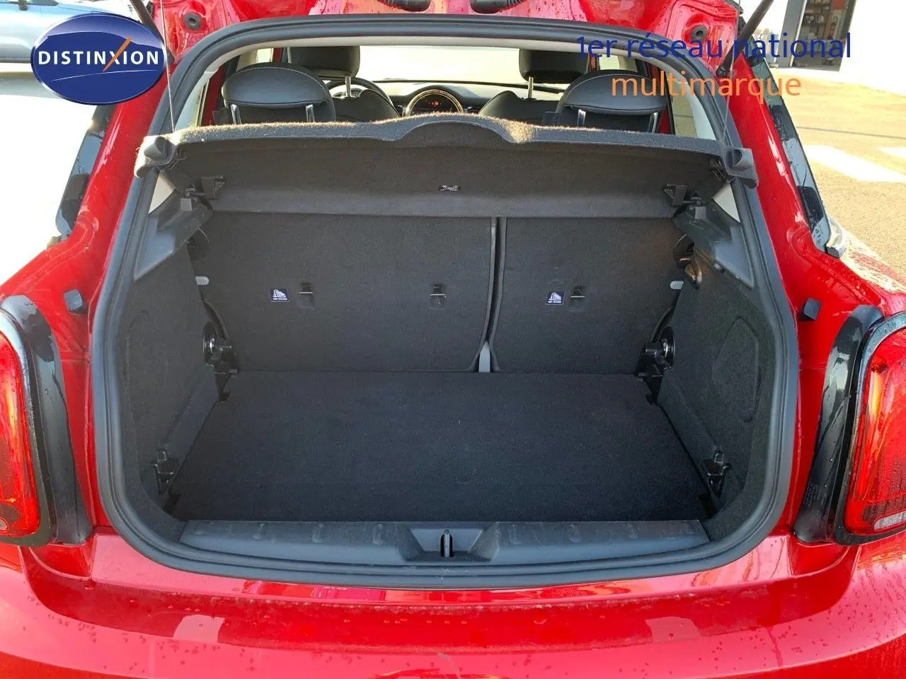 Coffre ouvert d'une MINI rouge chili 2023, vue arrière montrant l'espace de chargement et l'intérieur noir.