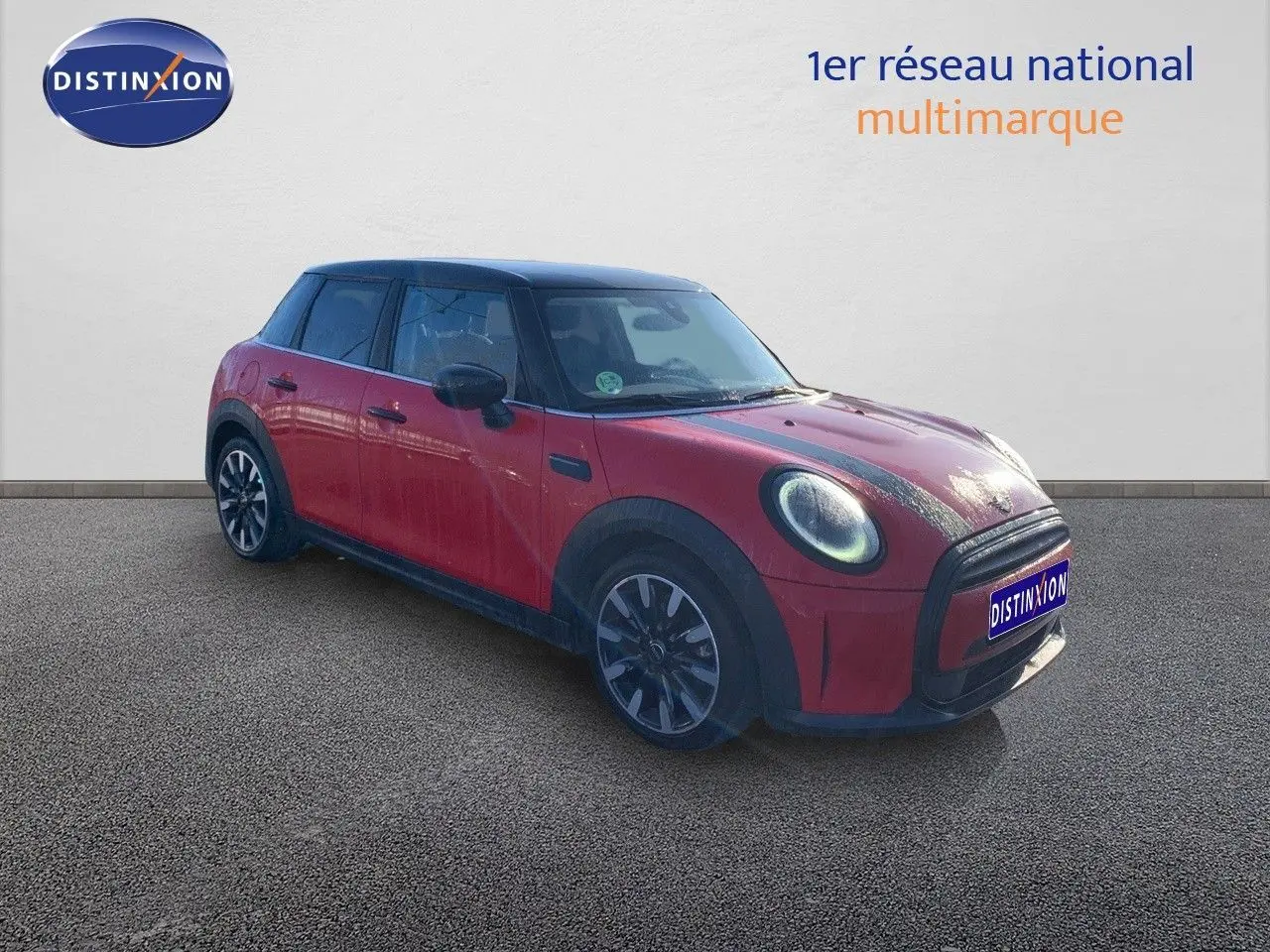 Vue 3/4 avant gauche d'une MINI 5 portes rouge chili avec toit noir et jantes alliage bicolores.