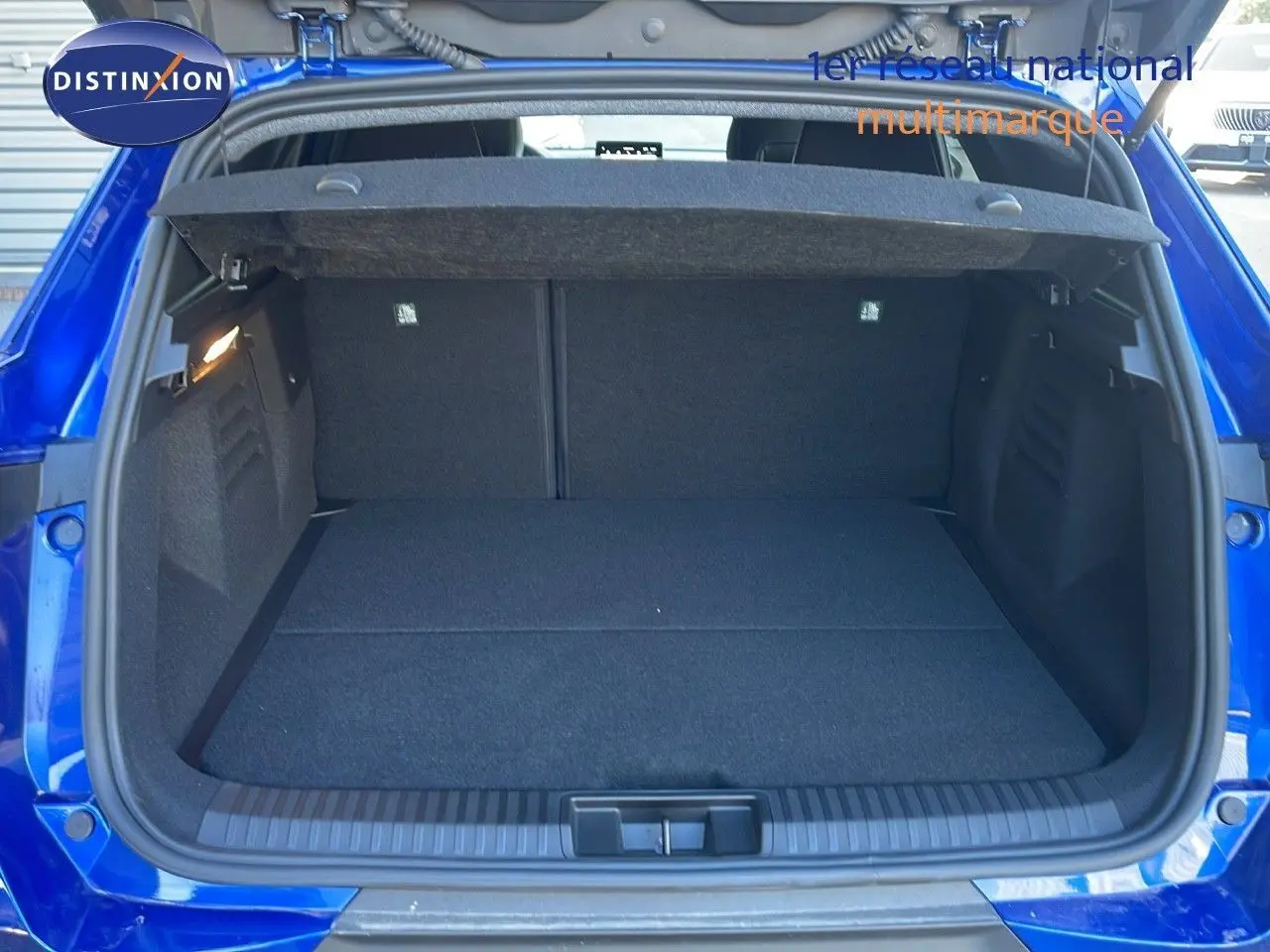 Coffre ouvert vu de l'arrière d'une Renault SYMBIOZ bleu iron metal, montrant l'espace de chargement vide.