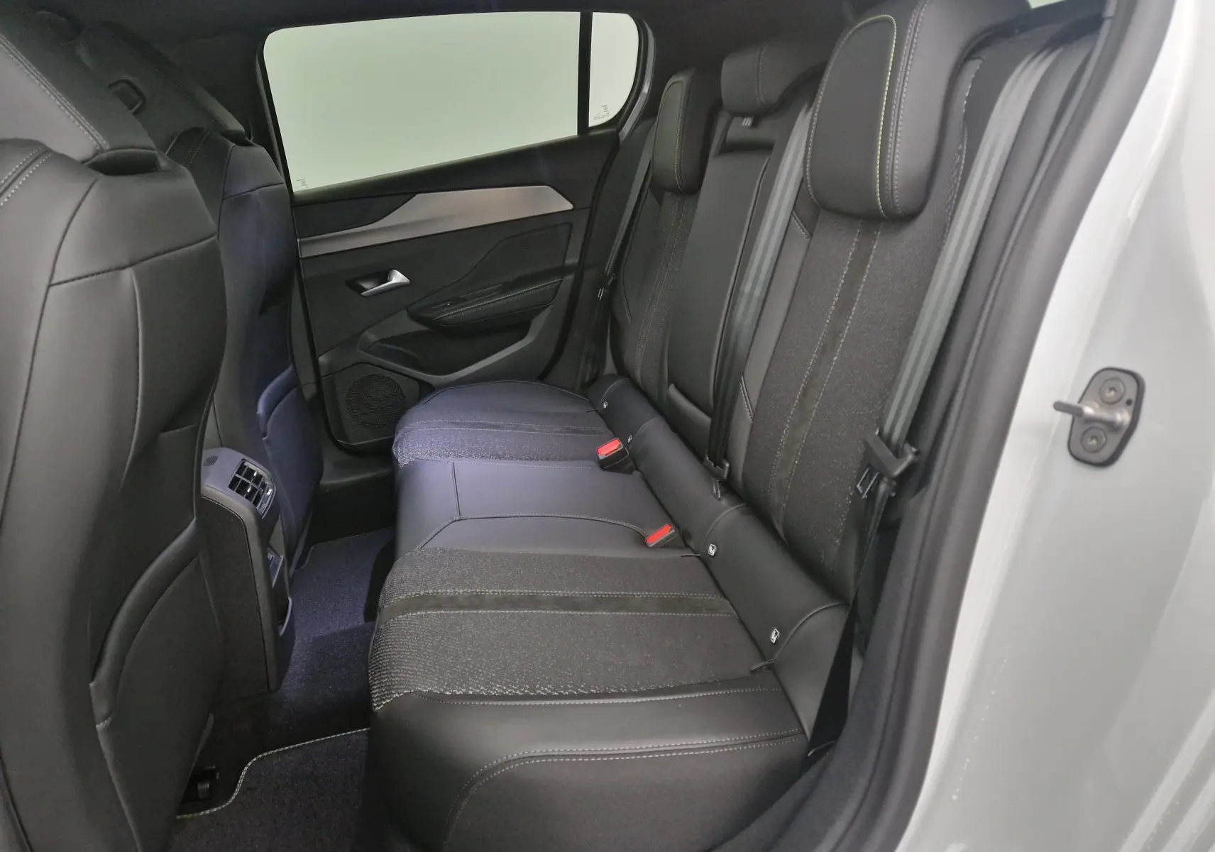 Vue intérieure côté droit des sièges arrière en tissu et cuir noir du Peugeot 308 blanc Okenite 2025.