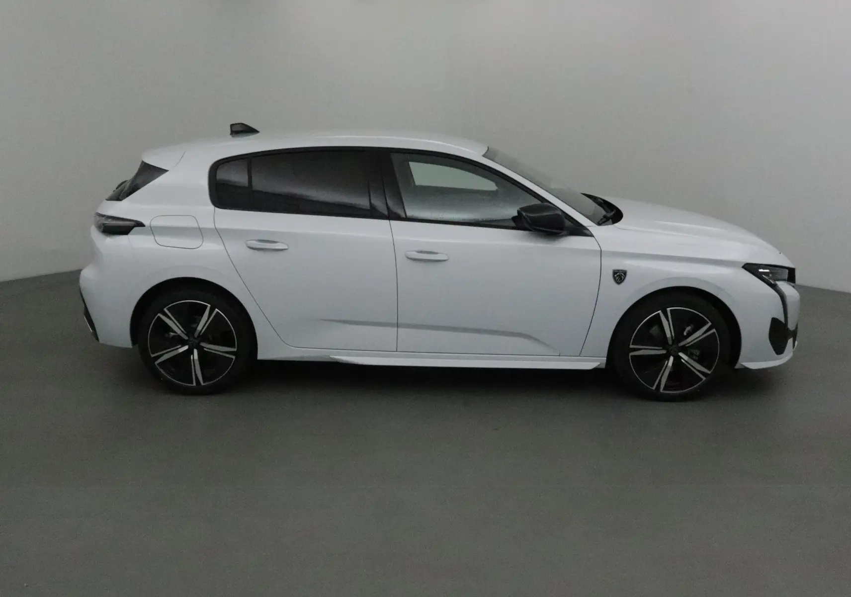 Profil côté droit d'une Peugeot 308 blanche Okenite 2025, avec jantes alliage noires et vitres teintées.