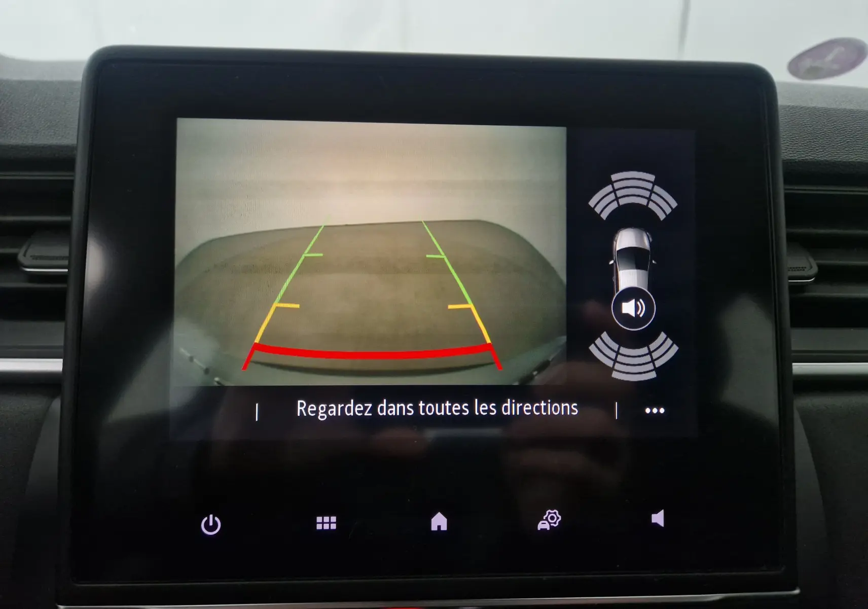 Écran de caméra de recul du Renault Captur gris Highland, avec guidage de stationnement et alertes sonores visibles.