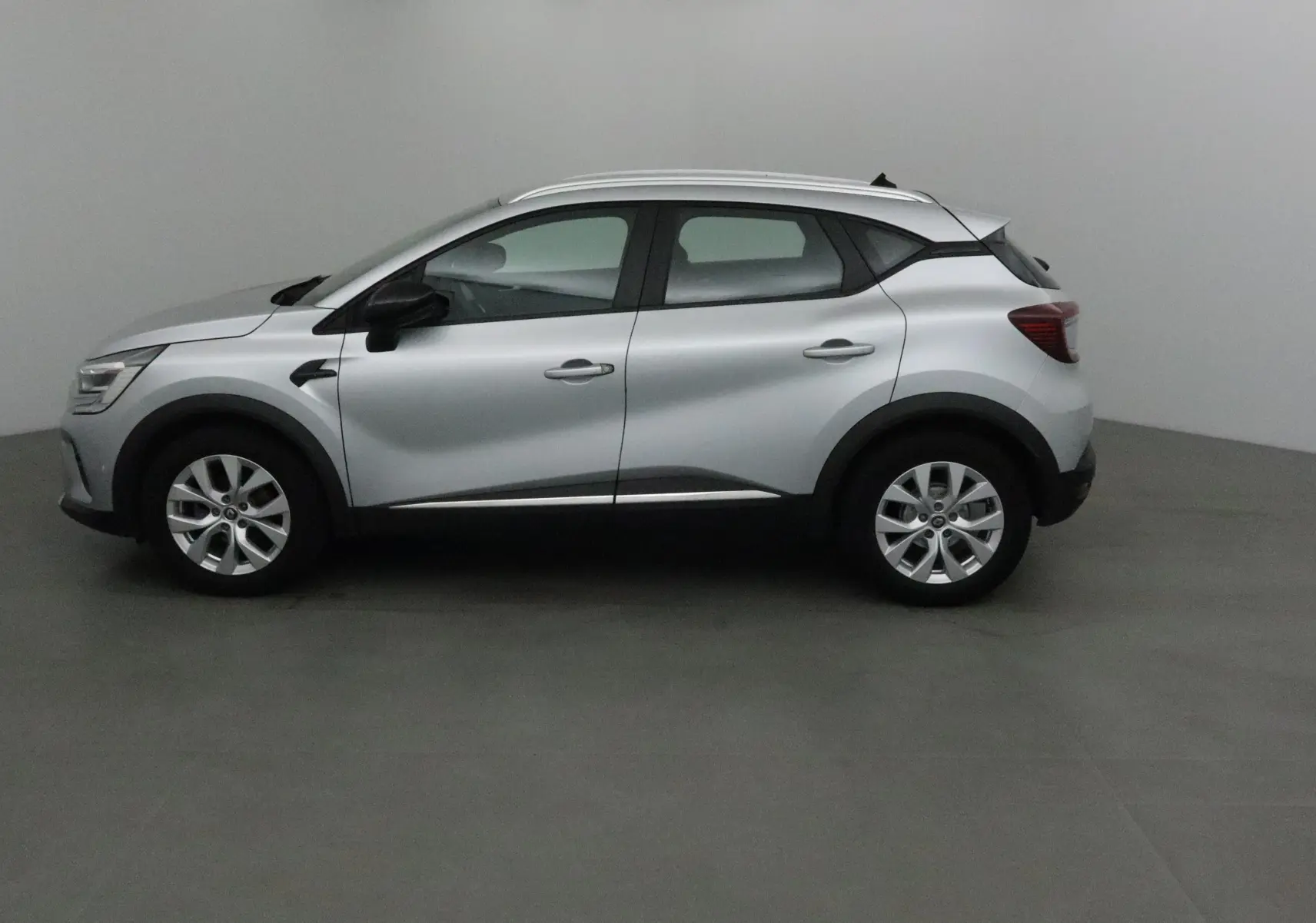 Profil côté gauche d'un Renault Captur gris Highland 2020, avec jantes alliage 17 pouces et protections noires.