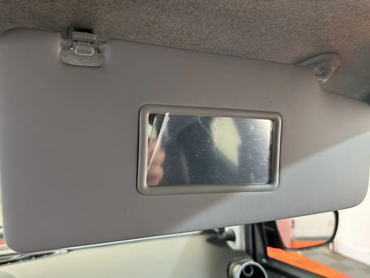 Détail du pare-soleil gris avec miroir intégré côté conducteur de l'AIXAM AMBITION 0.5 CITY SPORT rouge, vue intérieure.