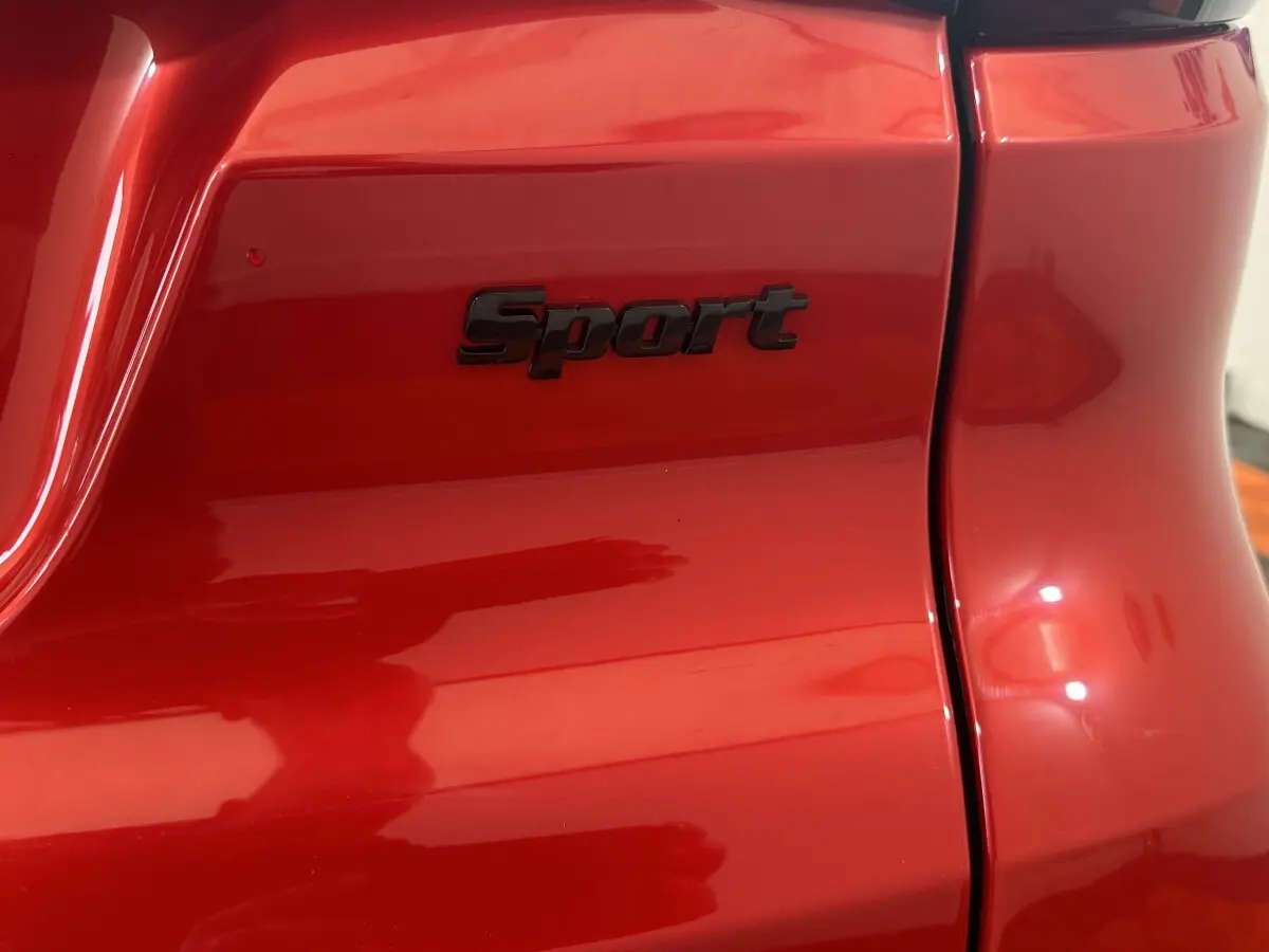Gros plan sur l'arrière droit rouge de l'AIXAM AMBITION 0.5 CITY SPORT avec logo "Sport" noir brillant.