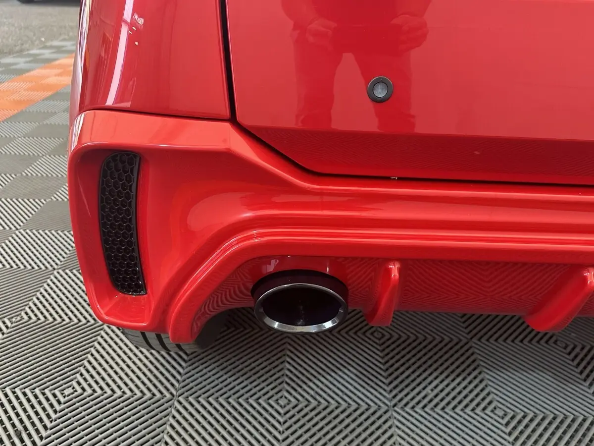 Gros plan sur l’échappement arrière droit d’une Aixam Ambition 0.5 City Sport rouge, soulignant le diffuseur et la sortie chromée.