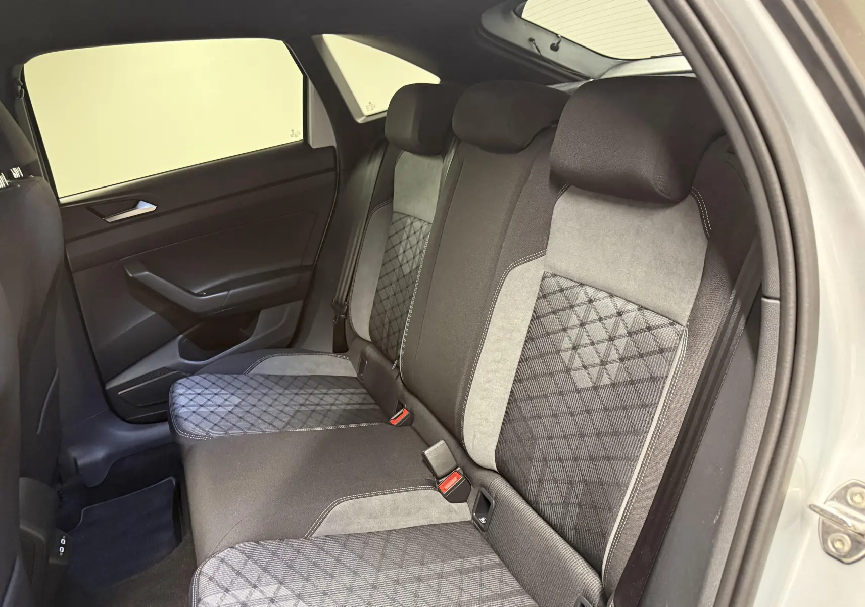 Vue intérieure côté droit des sièges arrière du Volkswagen Taigo 1.5 TSI 150 DSG7 R-Line Edition avec sellerie tissu gris et noir.