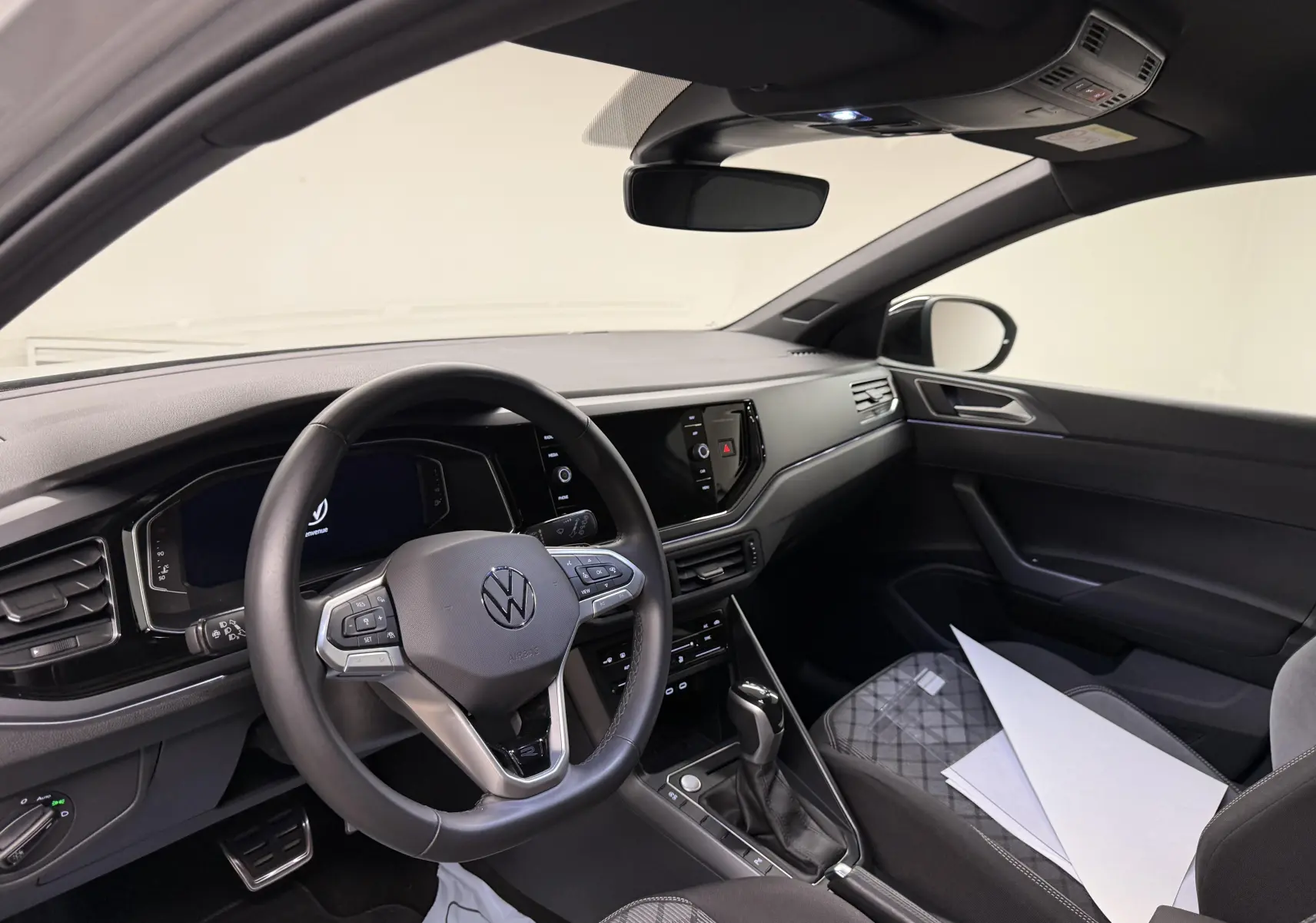 Vue intérieure côté conducteur du Volkswagen Taigo 1.5 TSI 150 DSG7 R-Line Edition, tableau de bord et volant noirs.