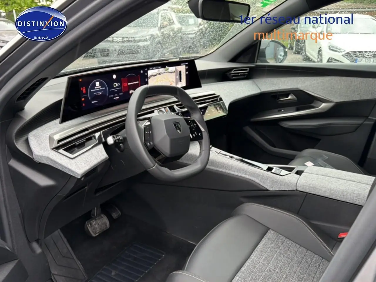 Vue intérieure côté conducteur du Peugeot 5008 Hybrid 145 allure e-dcs6 2025 avec tableau de bord gris et volant cuir noir.