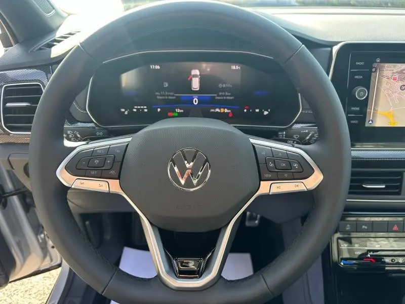 Vue centrée sur le volant cuir multifonction du Volkswagen T-Cross argenté, avec tableau de bord numérique et écran tactile visible.