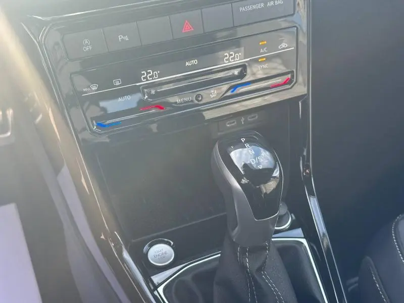 Gros plan sur la console centrale argentée du Volkswagen T-Cross 2026, avec levier de boîte auto et commandes climatisation digitales.