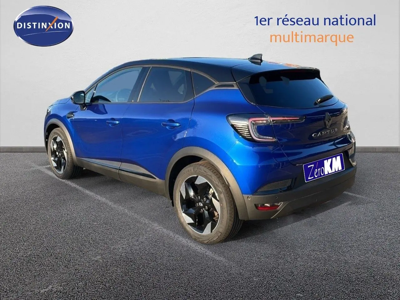 Vue 3/4 arrière gauche d'un Renault Captur E-Tech hybride bleu Iron Metal avec toit noir et jantes biton.