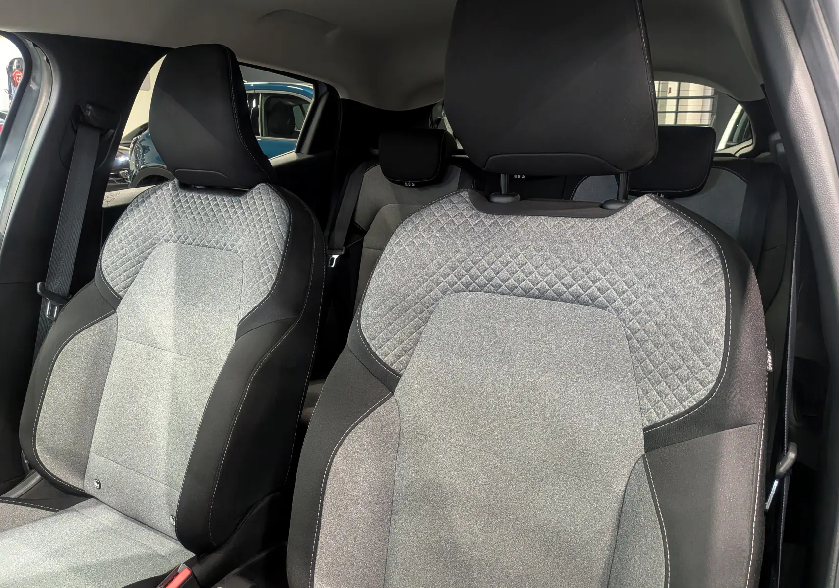 Gros plan sur les sièges avant en tissu gris clair et noir de la Renault Clio V Blue dCi 100 Evolution 2025.