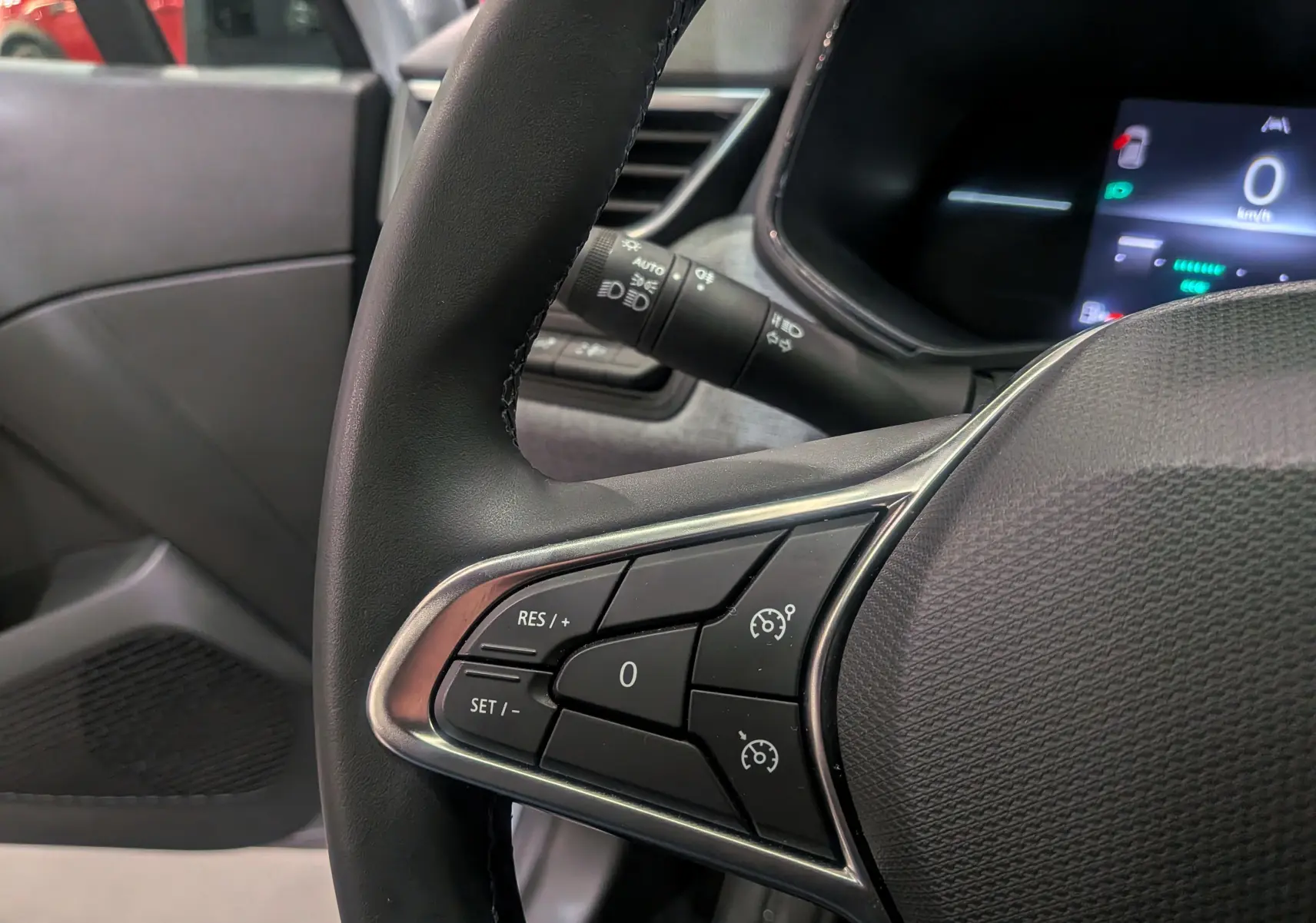 Gros plan sur le volant noir de la Renault Clio V gris Rafale, montrant les commandes de régulateur de vitesse.