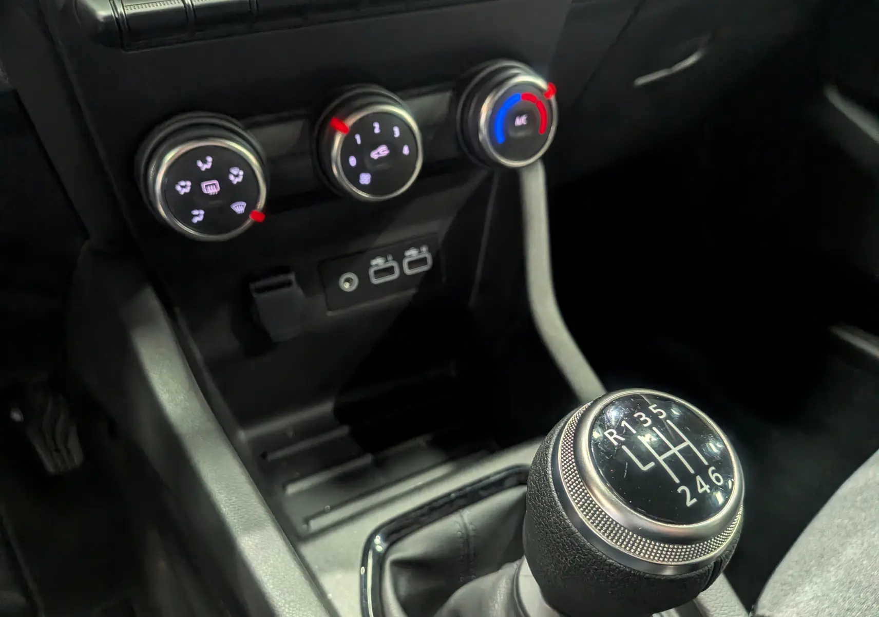 Gros plan sur le levier de vitesses manuel et les commandes de climatisation d'une Renault Clio V Gris Rafale 2025.