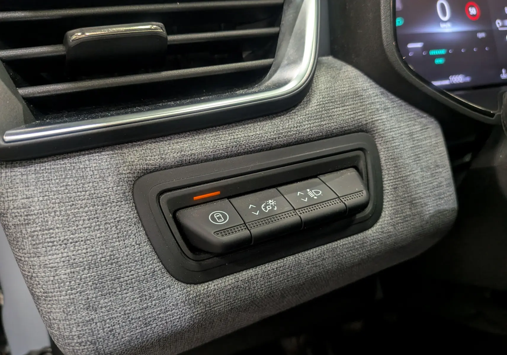 Gros plan sur les commandes d'éclairage et de verrouillage intégrées dans la garniture grise du tableau de bord Renault Clio V 2025.