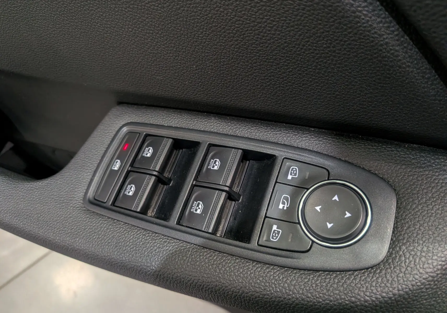 Gros plan sur les commandes des vitres électriques et réglages des rétroviseurs côté conducteur d'une Renault Clio V Gris Rafale.