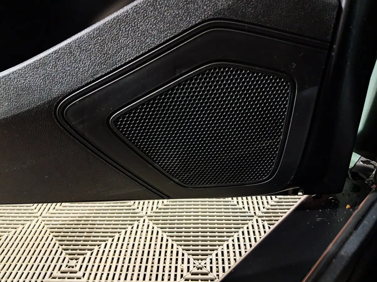 Gros plan sur le haut-parleur intégré à la porte côté conducteur d'une Aixam Minauto E chic 2026, intérieur noir.