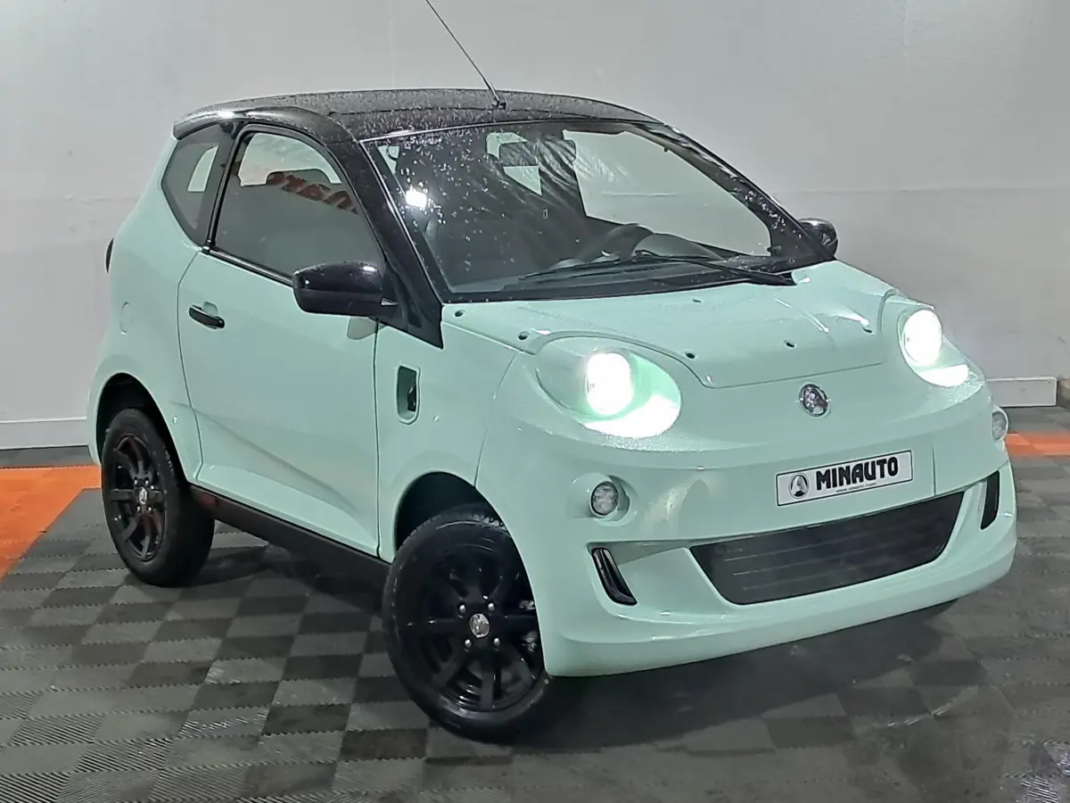 Vue 3/4 avant d'une Aixam Minauto E chic électrique 2026 vert clair avec toit noir et jantes noires.