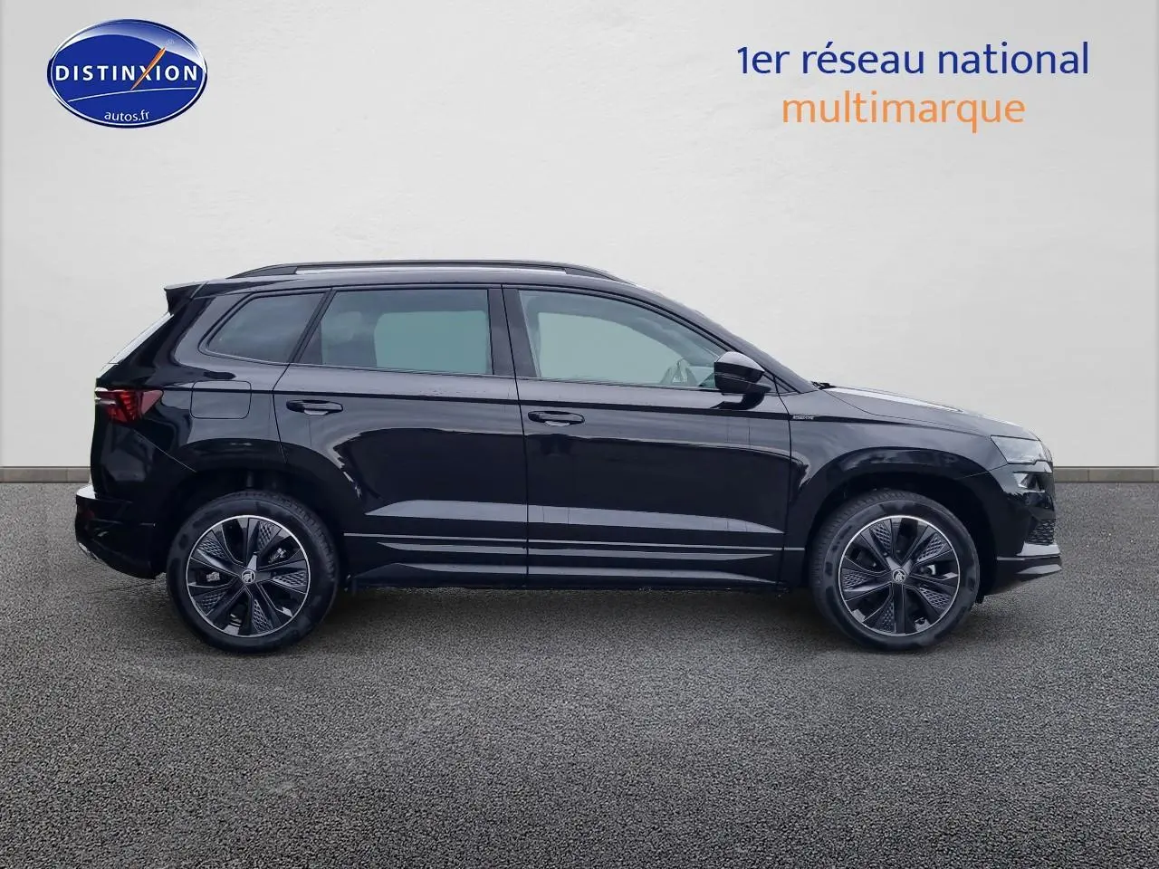 Profil côté gauche d'un SUV SKODA KAROQ noir 2025 avec jantes alu et barres de toit visibles sur fond neutre.