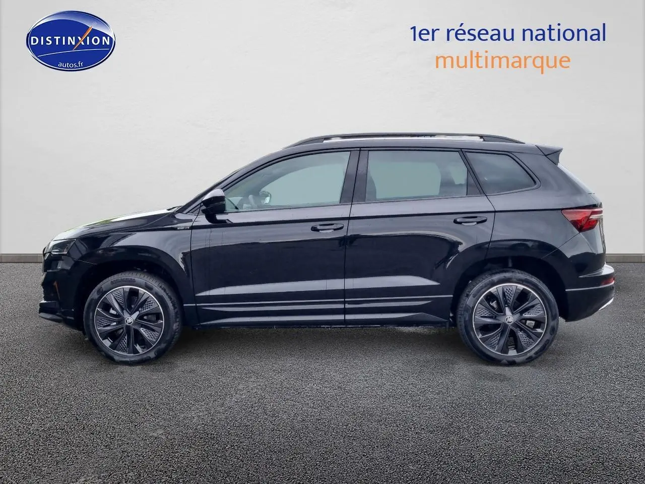 Profil côté gauche d'un SUV SKODA KAROQ noir 2025 avec jantes alu et barres de toit visibles.