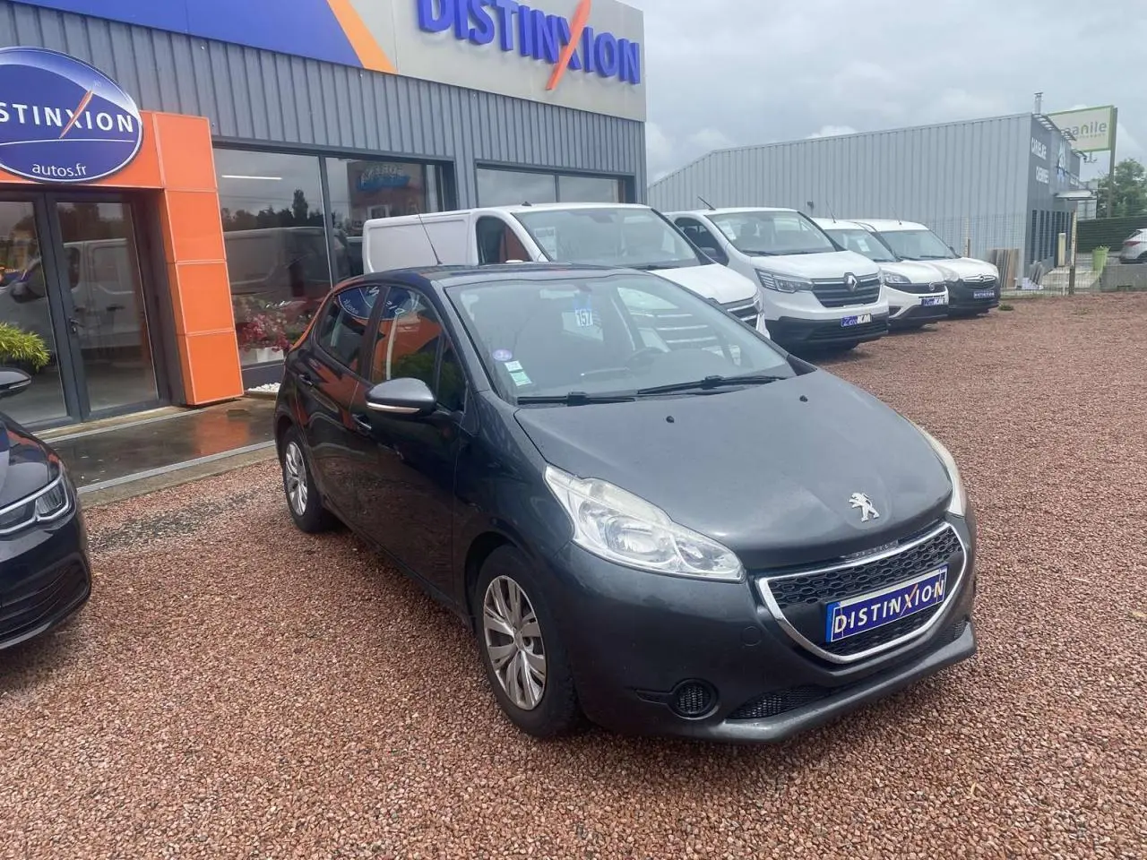Peugeot 208 gris shark vue 3/4 avant sur parking devant concession Distinxion.