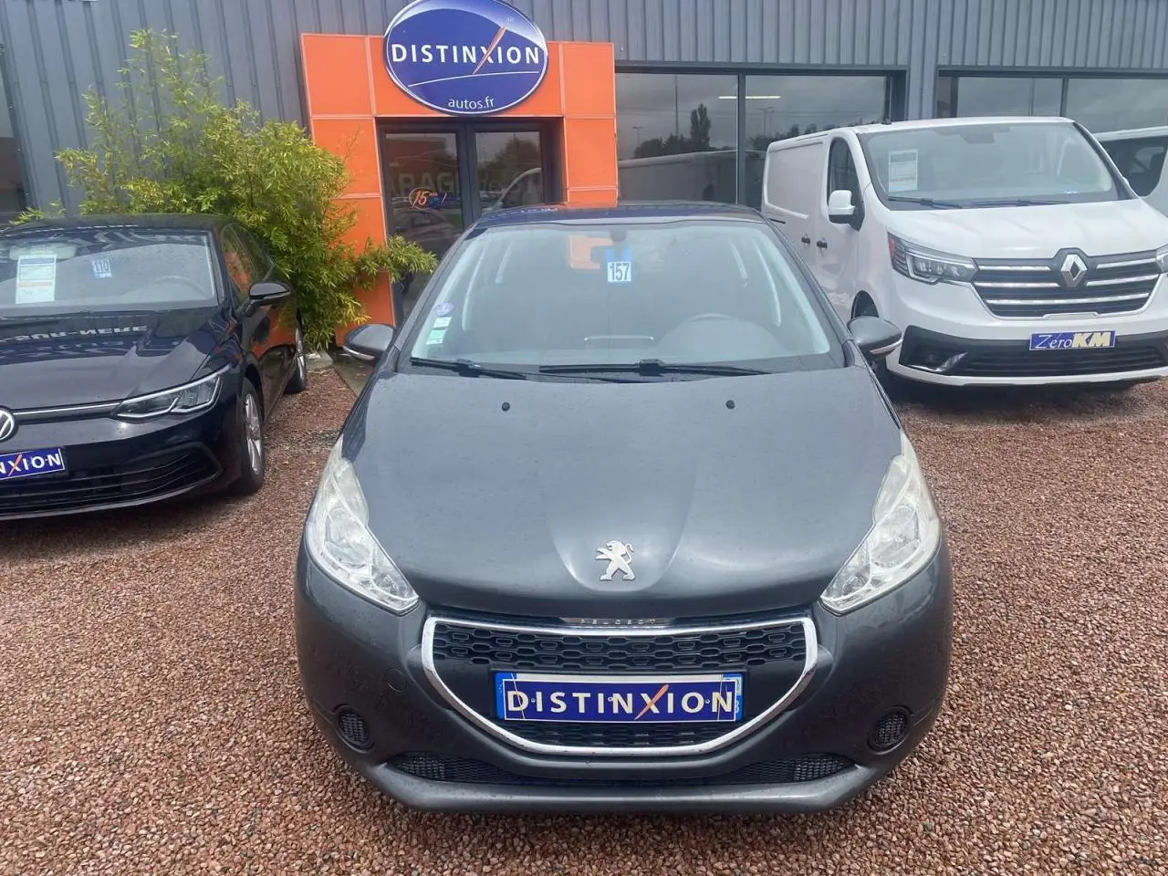 Vue frontale d'une Peugeot 208 gris shark 2013 avec calandre chromée et logo lion visible sur le capot.