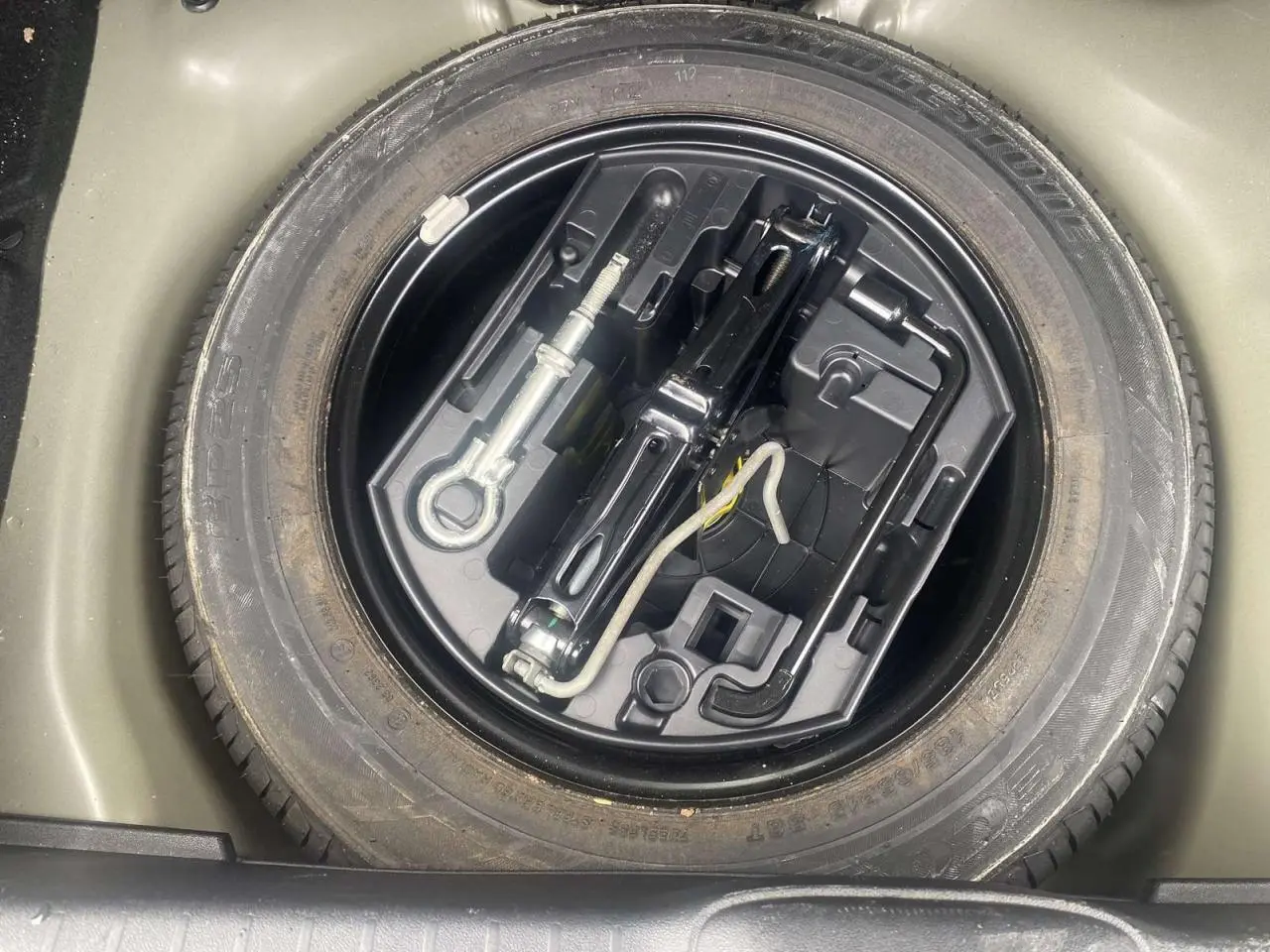 Roue de secours acier 15 pouces avec kit de démontage dans le coffre d'une Peugeot 208 gris Shark 2013.