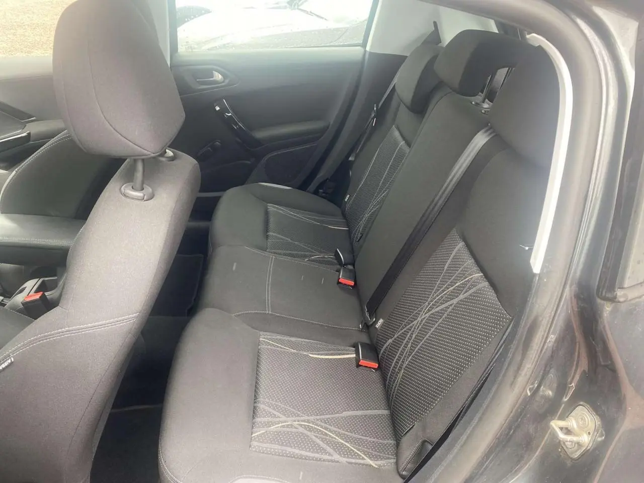 Vue intérieure côté droit des sièges arrière noirs avec motifs gris d'une Peugeot 208 gris shark de 2013.
