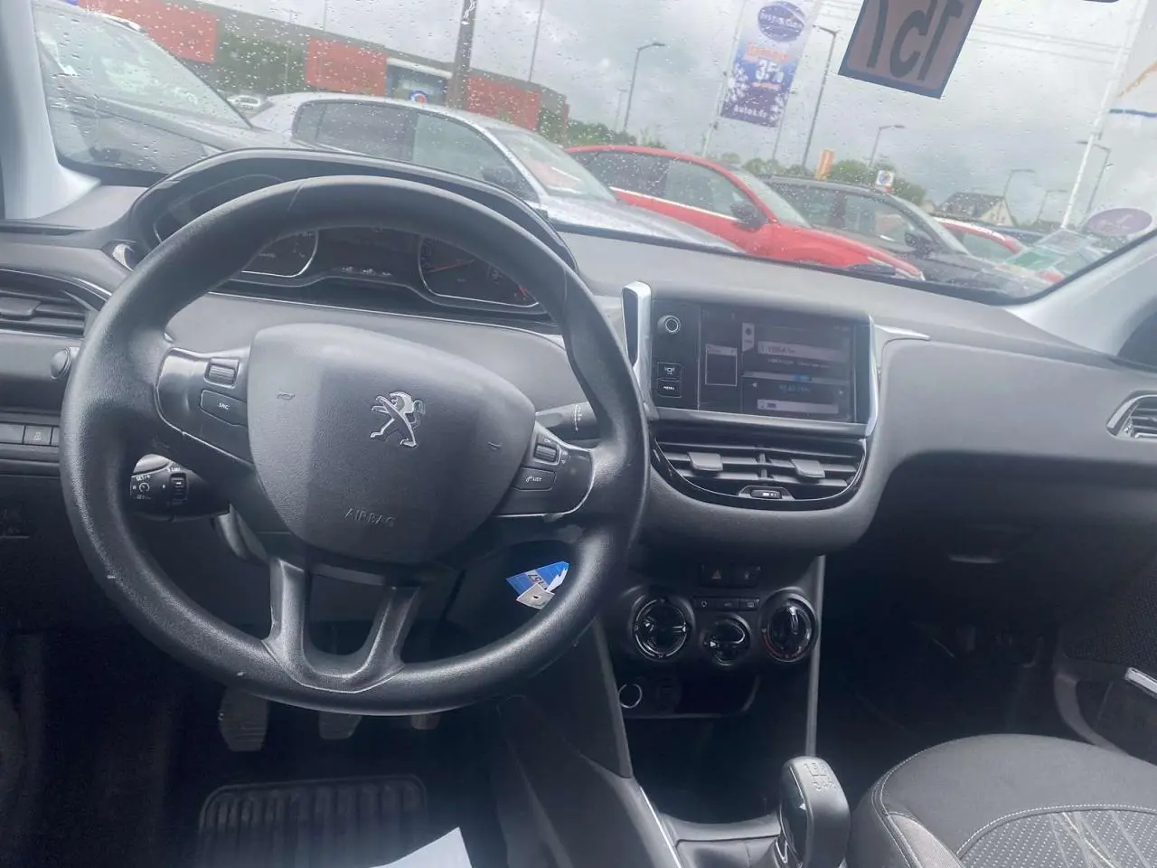 Vue intérieure de face du volant multifonction et de l'écran tactile du tableau de bord d'une Peugeot 208 gris shark 2013.