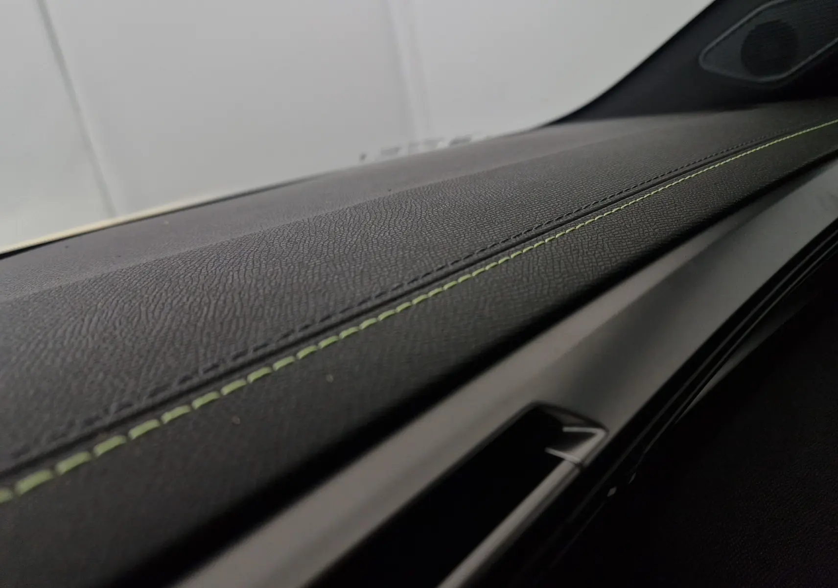 Gros plan sur la finition intérieure noire avec surpiqûres vertes du tableau de bord de la Peugeot 308 GT 2025.