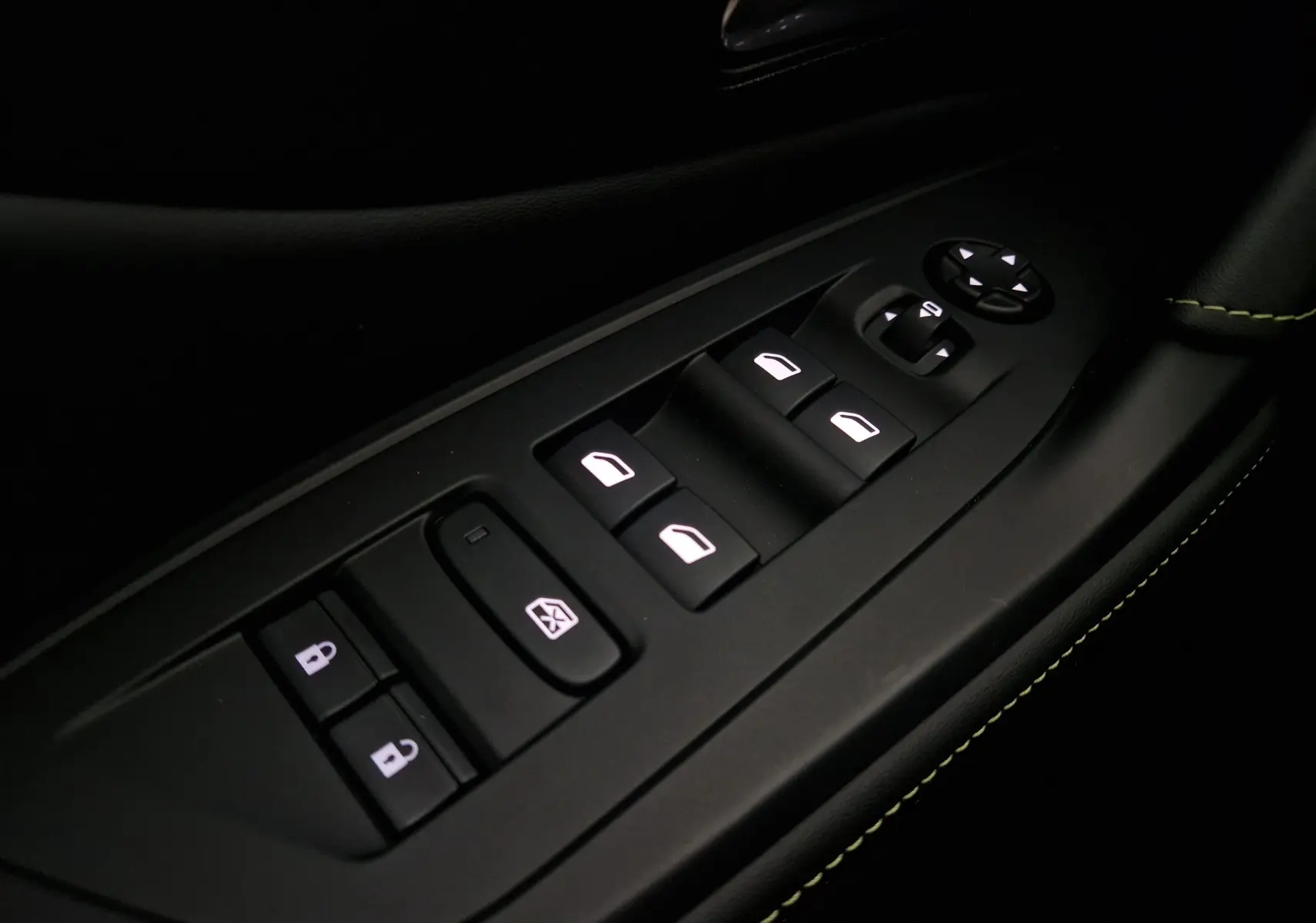 Gros plan sur les commandes de lève-vitres et rétroviseurs côté conducteur d'une Peugeot 308 GT+ blanc Okenite, avec surpiqûres vertes.