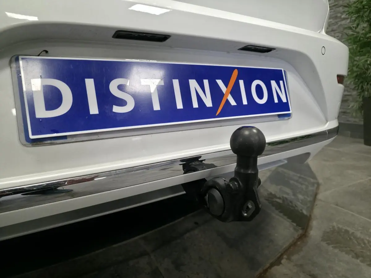 Gros plan sur l'attelage rabattable noir à l'arrière d'une Volkswagen Arteon blanche avec plaque Distinxion.