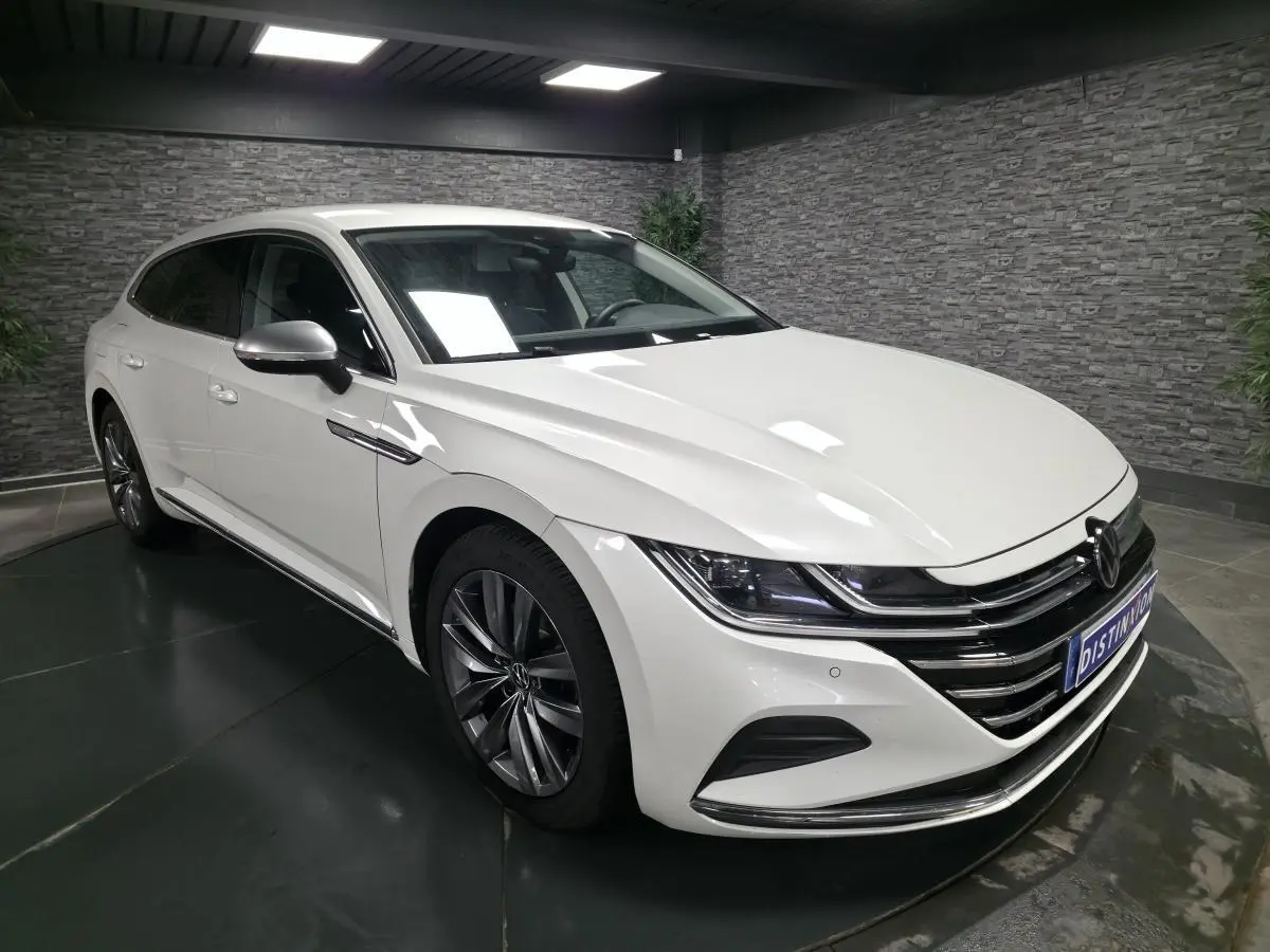 Volkswagen Arteon blanc nacré vu en 3/4 avant droit, avec calandre chromée et jantes alliage 18 pouces.