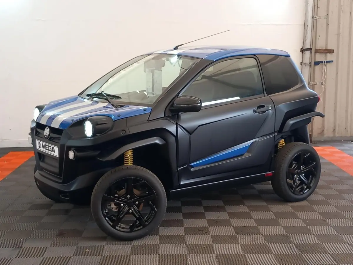 Vue 3/4 avant droite de l'AIXAM MEGA E-SCOUTY EVO bleu avec bandes blanches, jantes noires et suspensions jaunes visibles.