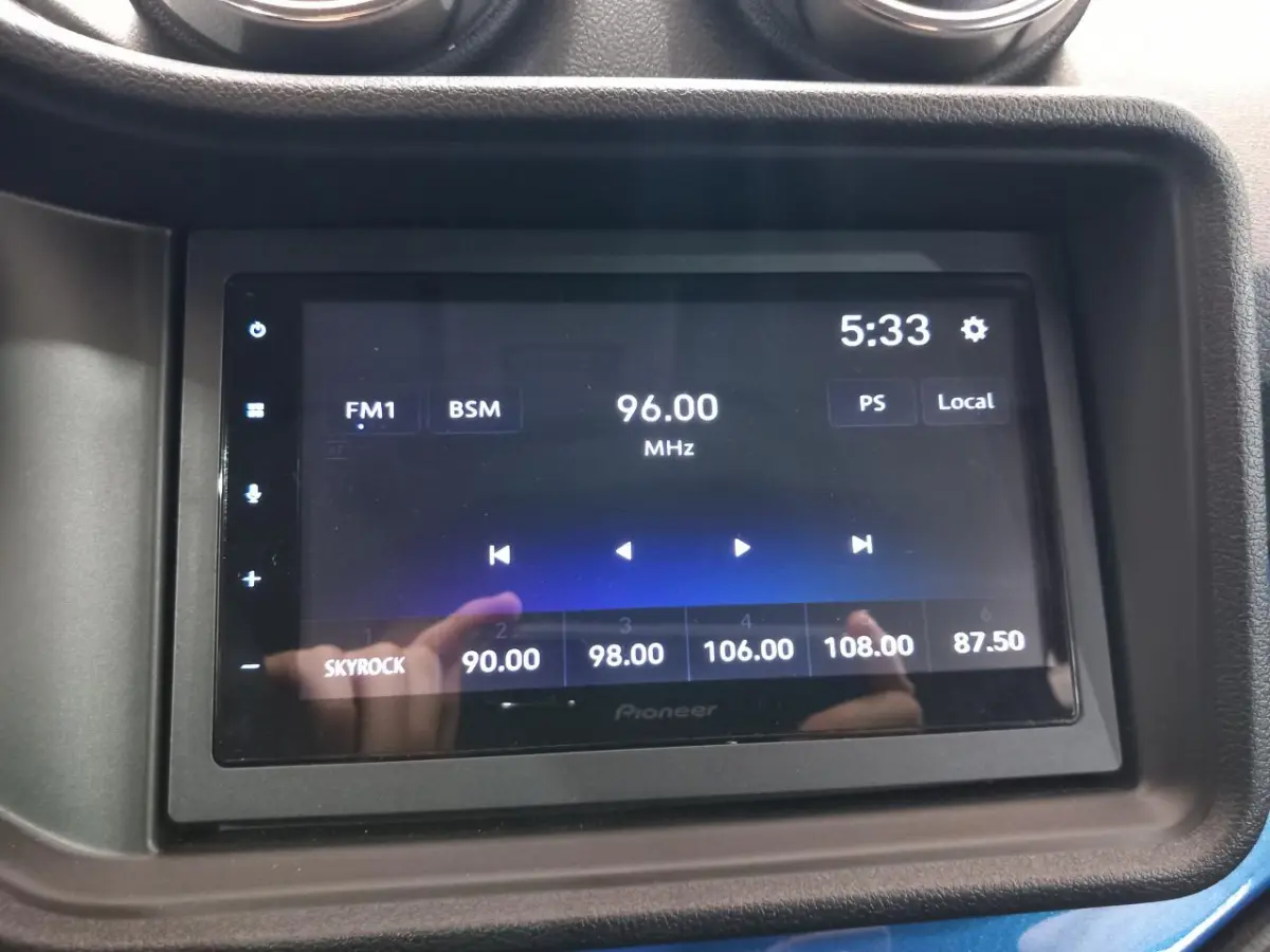 Écran tactile multimédia Pioneer dans l'habitacle de l'AIXAM MEGA bleu, affichant une radio FM à 96 MHz.