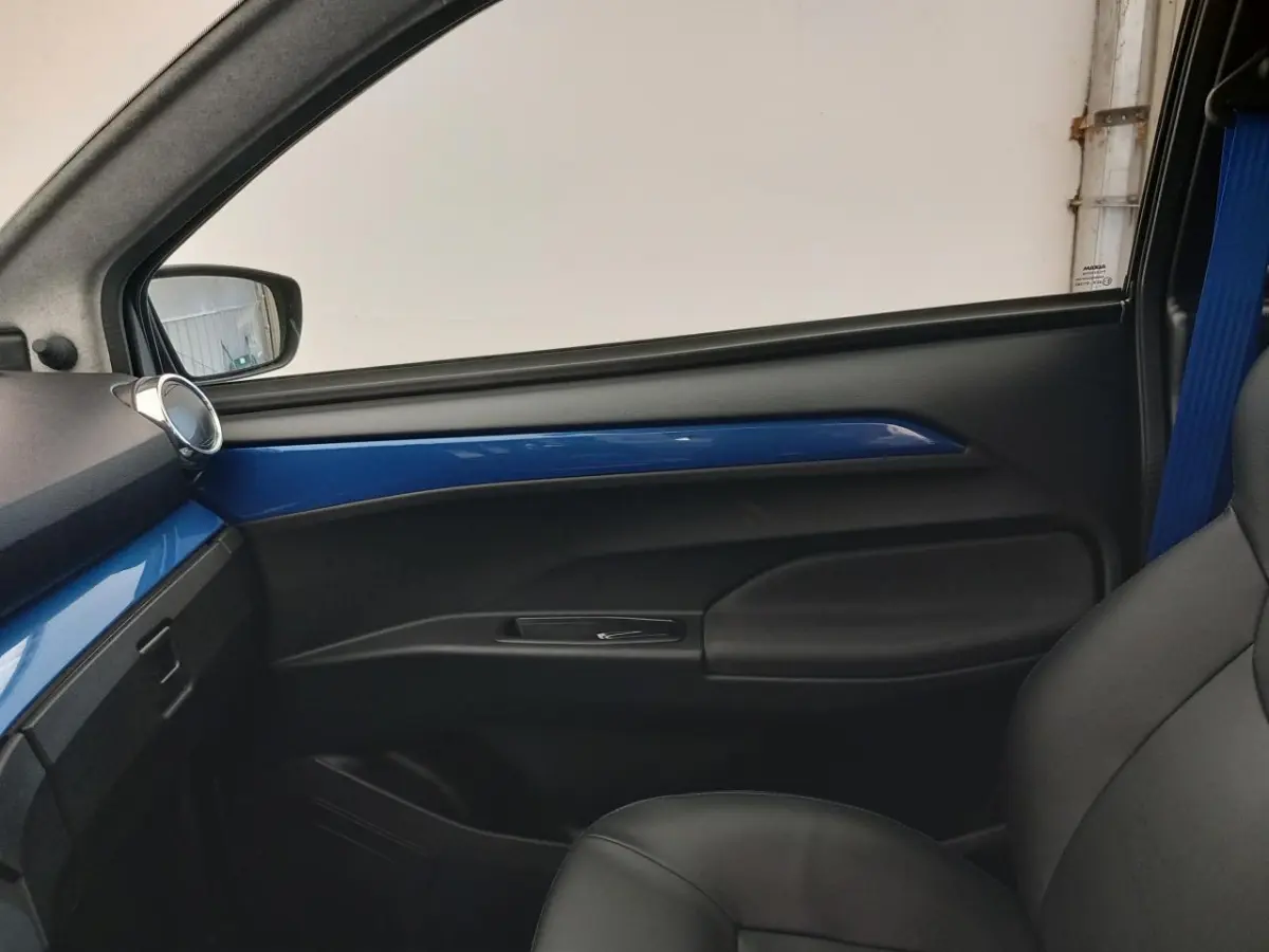 Vue intérieure côté passager de l’AIXAM MEGA E-SCOUTY EVO 2026 avec garniture bleue et siège noir.