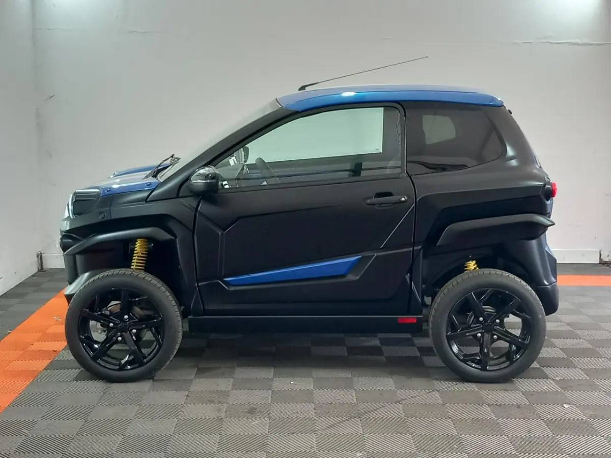 Vue de profil côté gauche d'une Aixam MEGA E-Scouty Evo 2026 bleu et noir avec suspensions jaunes et jantes noires.