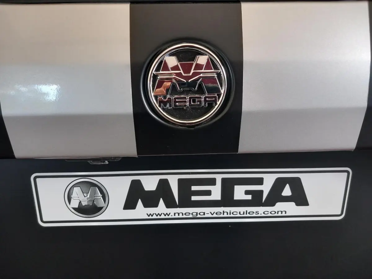 Gros plan sur l'arrière du véhicule bleu AIXAM MEGA avec logo et plaque d'immatriculation MEGA visible.