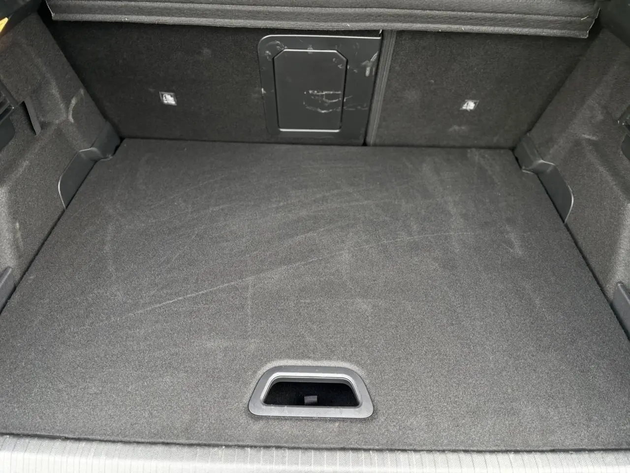 Coffre spacieux vu de dessus, revêtement gris foncé avec trappe d’accès au fond sur Citroën C4 Hybrid 2025.