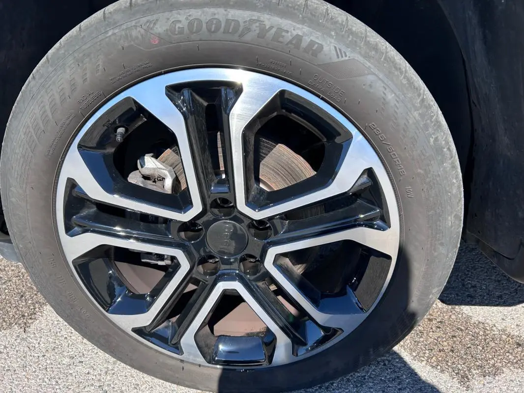 Gros plan sur la jante alliage 18 pouces noire et argentée du Jeep Compass gris 2024, pneu Goodyear visible.
