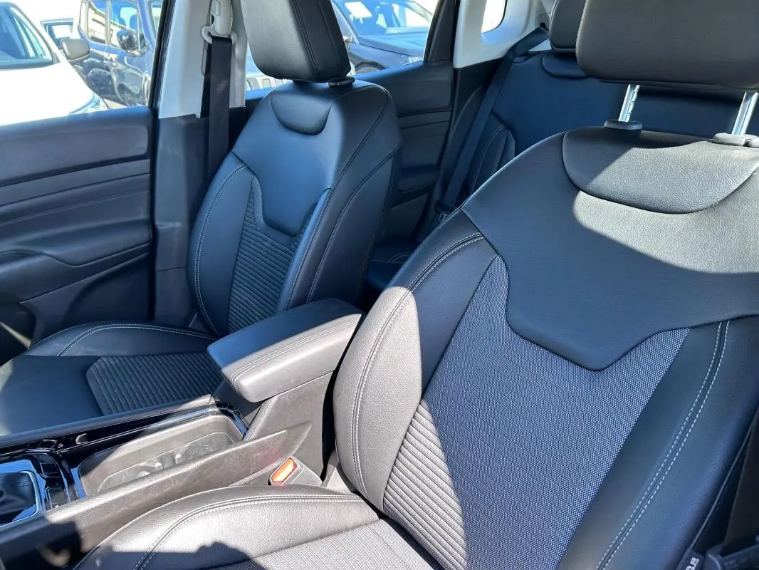 Vue intérieure rapprochée des sièges avant noirs en cuir du Jeep Compass 2024, avec accoudoir central visible.