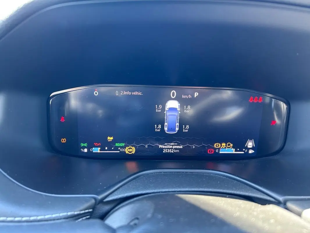 Vue rapprochée du tableau de bord numérique du Jeep Compass gris 2024 affichant la pression des pneus et les alertes.