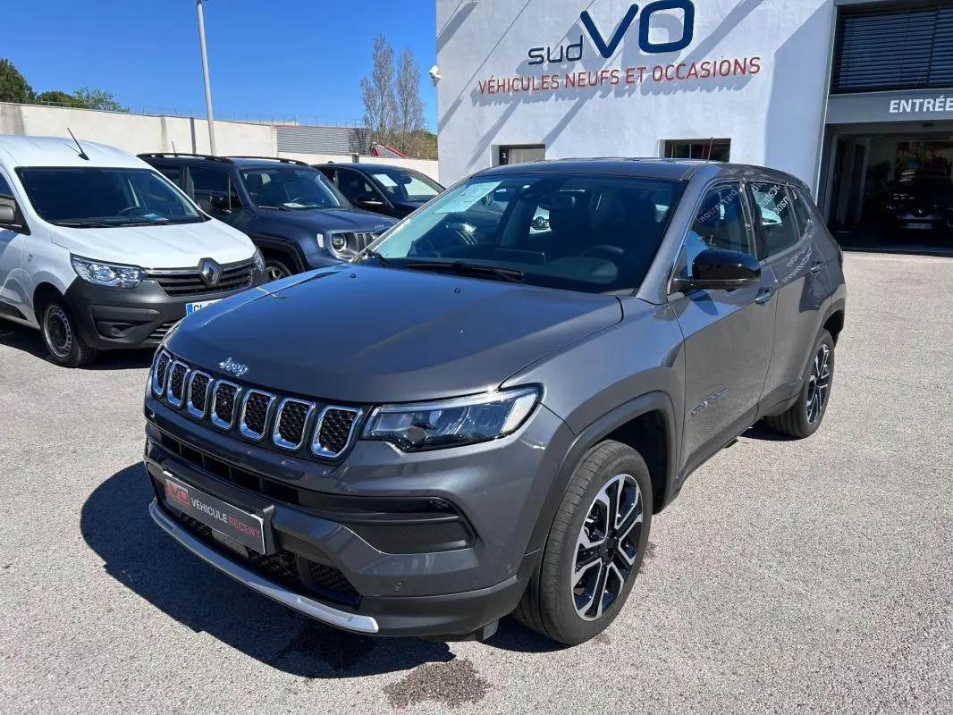 Jeep Compass gris 3/4 avant droit, jantes alliage 18 pouces, calandre distinctive et phares LED visibles.