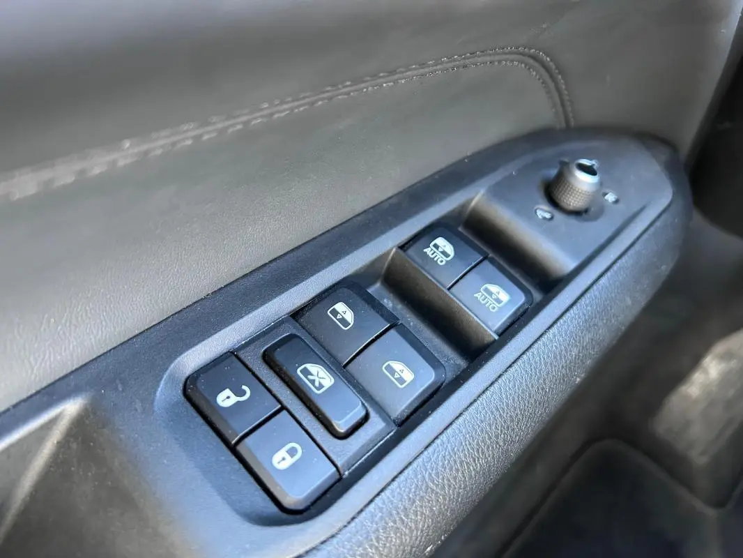 Gros plan sur les commandes des vitres et rétroviseurs côté conducteur du Jeep Compass gris 2024.