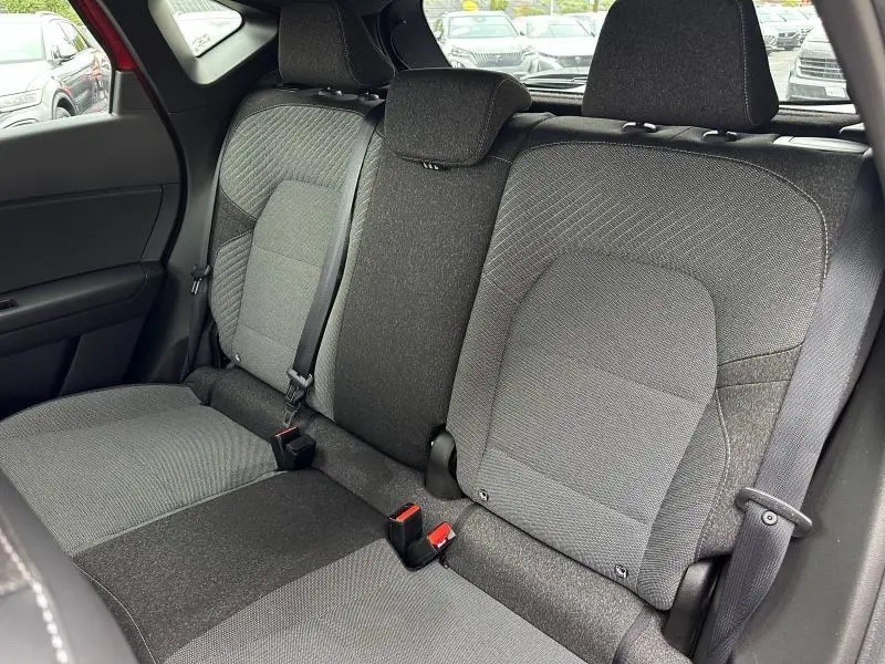 Vue intérieure arrière du Renault Captur 2025, sièges tissu gris avec ceintures de sécurité visibles.