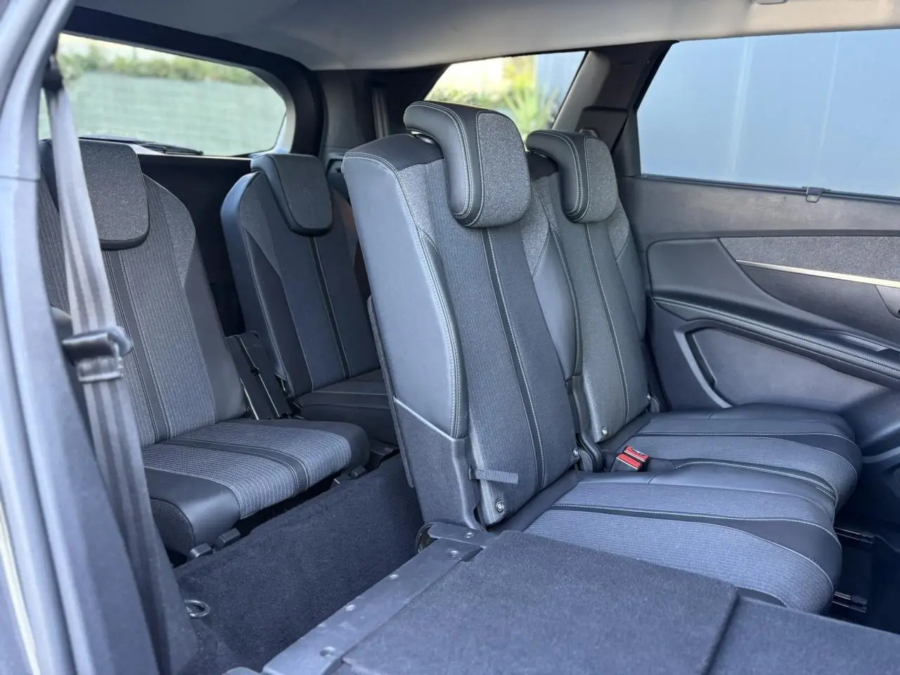 Vue intérieure côté droit des sièges arrière et troisième rangée du Peugeot 5008 2022 en tissu gris avec appuie-têtes.