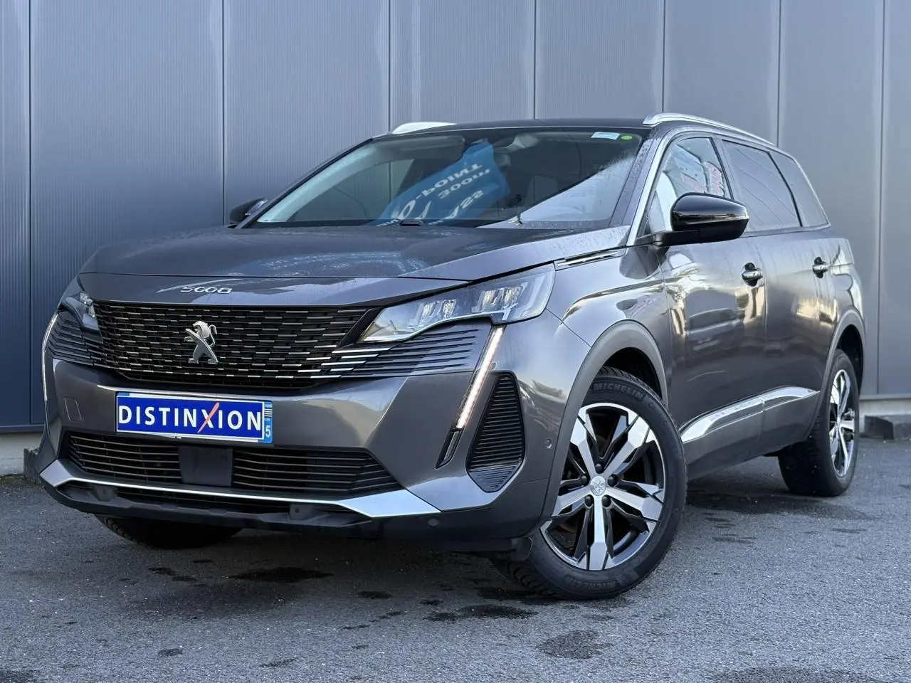 Peugeot 5008 gris Platinium en 3/4 avant droit, avec calandre noire et jantes alliage bi-ton 18 pouces.
