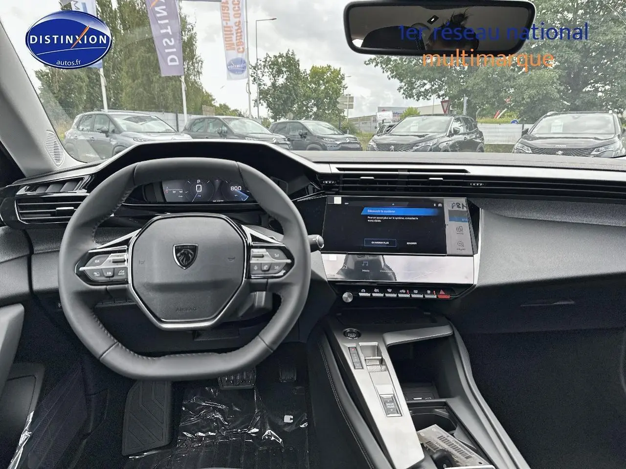 Vue intérieure du tableau de bord et volant multifonction de la Peugeot 308 noire, avec écran tactile central allumé.